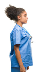 Poster - Young afro american doctor woman over isolated background looking to side, relax profile pose with natural face with confident smile.