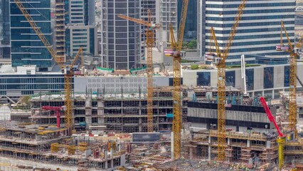 Wall Mural - Large construction site with many working cranes timelapse during many hours. Top aerial view of big development of residential and office district in Business bay, Dubai