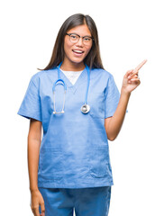 Sticker - Young asian doctor woman over isolated background with a big smile on face, pointing with hand and finger to the side looking at the camera.