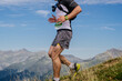 © sports photos - female athlete running from mountainside in leggings, mountain marathon race, background sky