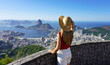 © zigres - Stylish tourist woman on terrace in Rio de Janeiro with the famous Guanabara bay and the cityscape of Rio de Janeiro, Brazil