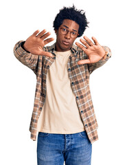 Wall Mural - Handsome african american man with afro hair wearing casual clothes and glasses doing frame using hands palms and fingers, camera perspective