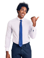 Canvas Print - Handsome african american man with afro hair wearing business clothes smiling with happy face looking and pointing to the side with thumb up.