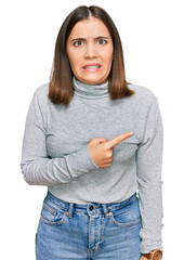 Poster - Young beautiful woman wearing casual turtleneck sweater pointing aside worried and nervous with forefinger, concerned and surprised expression