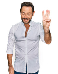 Wall Mural - Middle age man wearing casual clothes showing and pointing up with fingers number three while smiling confident and happy.