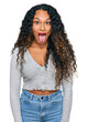© Krakenimages.com - Young hispanic woman with curly hair wearing casual clothes sticking tongue out happy with funny expression. emotion concept.