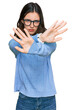 © Krakenimages.com - Young beautiful woman wearing casual clothes and glasses rejection expression crossing arms and palms doing negative sign, angry face