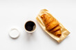 One disposible paper cup of coffee to go with croissant