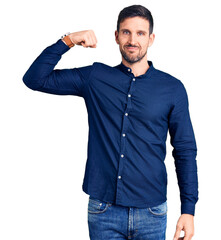 Canvas Print - Young handsome man wearing casual shirt strong person showing arm muscle, confident and proud of power