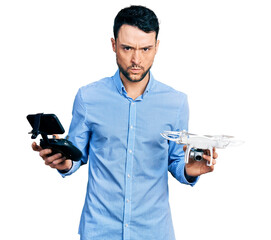 Poster - Hispanic man with beard using drone with remote control skeptic and nervous, frowning upset because of problem. negative person.