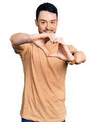 Canvas Print - Hispanic man with beard wearing casual t shirt smiling in love doing heart symbol shape with hands. romantic concept.