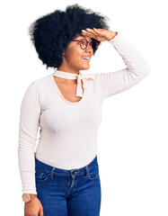 Sticker - Young african american girl wearing casual clothes and glasses very happy and smiling looking far away with hand over head. searching concept.