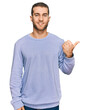 © Krakenimages.com - Young caucasian man wearing casual clothes smiling with happy face looking and pointing to the side with thumb up.