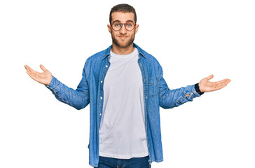 Poster - Young caucasian man wearing casual clothes clueless and confused expression with arms and hands raised. doubt concept.