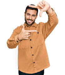 Poster - Young hispanic man wearing casual clothes smiling making frame with hands and fingers with happy face. creativity and photography concept.