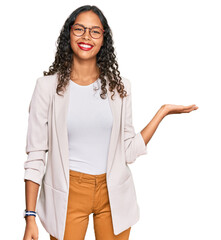 Canvas Print - Young african american girl wearing business clothes smiling cheerful presenting and pointing with palm of hand looking at the camera.