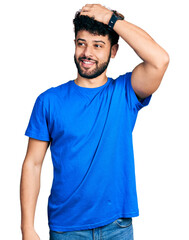 Poster - Young arab man with beard wearing casual blue t shirt smiling confident touching hair with hand up gesture, posing attractive and fashionable