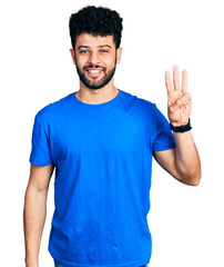 Canvas Print - Young arab man with beard wearing casual blue t shirt showing and pointing up with fingers number three while smiling confident and happy.