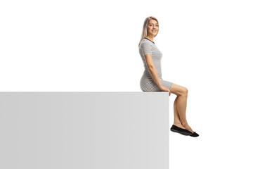 Poster - Casual young woman sitting on a white wall