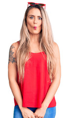 Canvas Print - Young beautiful blonde woman wearing sleeveless t-shirt and sunglasses making fish face with lips, crazy and comical gesture. funny expression.