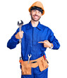 canvas print picture - Young hispanic man wearing electrician uniform holding wrench pointing finger to one self smiling happy and proud