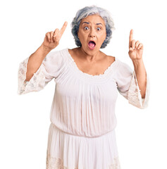 Sticker - Senior woman with gray hair wearing bohemian style smiling amazed and surprised and pointing up with fingers and raised arms.