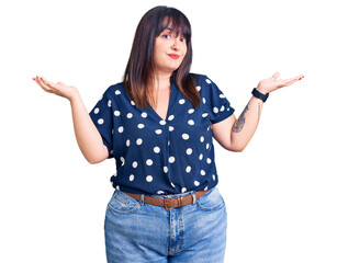 Sticker - Young plus size woman wearing casual clothes clueless and confused expression with arms and hands raised. doubt concept.