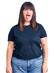 Wall Mural - Young plus size woman wearing casual clothes sticking tongue out happy with funny expression. emotion concept.