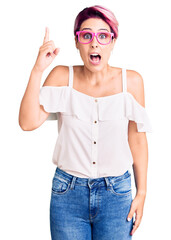 Canvas Print - Young beautiful woman with pink hair wearing casual clothes and glasses pointing finger up with successful idea. exited and happy. number one.