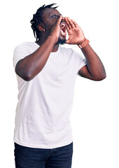 Poster - Young african american man with braids wearing casual white tshirt shouting angry out loud with hands over mouth