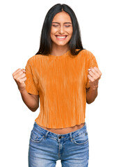 young brunette arab woman wearing casual clothes very happy and excited doing winner gesture with ar