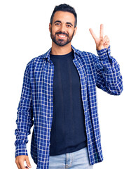 Young hispanic man wearing casual clothes showing and pointing up with fingers number two while smiling confident and happy.