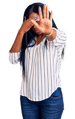 Sticker - Young african american woman wearing casual clothes and glasses covering eyes with hands and doing stop gesture with sad and fear expression. embarrassed and negative concept.