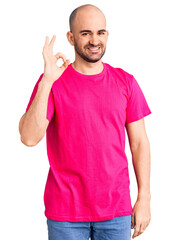 Poster - Young handsome man wearing casual t shirt smiling positive doing ok sign with hand and fingers. successful expression.