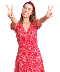 Canvas Print - Young beautiful girl wearing dress and diadem smiling with tongue out showing fingers of both hands doing victory sign. number two.