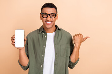 Sticker - Portrait of cheerful satisfied handsome man demonstrate smartphone touchscreen directing empty space isolated on beige color background