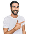 © Krakenimages.com - Young hispanic man wearing casual white t shirt cheerful with a smile of face pointing with hand and finger up to the side with happy and natural expression on face