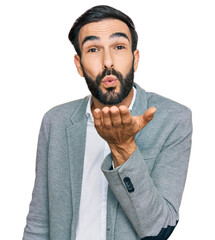 Wall Mural - Young hispanic man wearing business clothes looking at the camera blowing a kiss with hand on air being lovely and sexy. love expression.