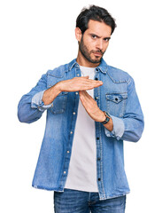 Wall Mural - Young hispanic man wearing casual clothes doing time out gesture with hands, frustrated and serious face