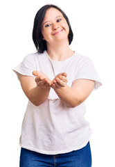 Sticker - Brunette woman with down syndrome wearing casual white tshirt smiling with hands palms together receiving or giving gesture. hold and protection