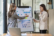 © ArLawKa - Two asian businesswoman sitting and consulting business inside modern office discussing presentation of startup project idea Analyze statistics and investment markets at the office.