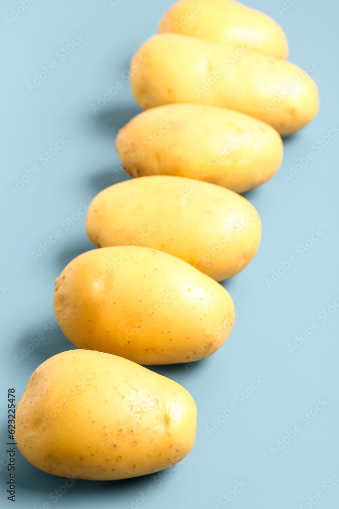 Raw potatoes on blue background