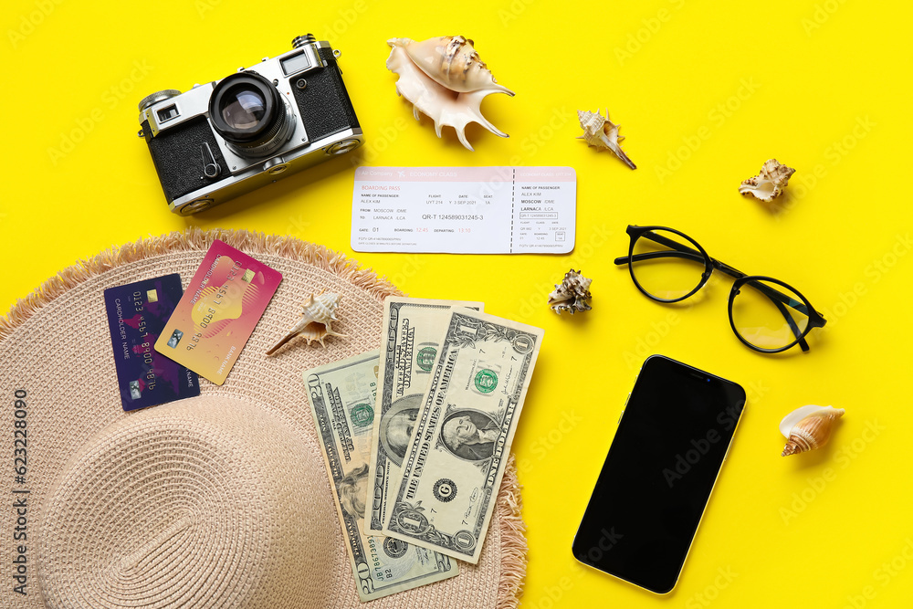 Composition with mobile phone, credit cards, ticket and seashells on yellow background
