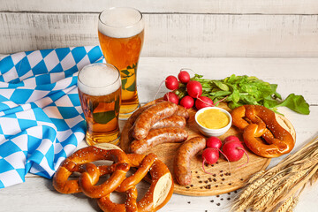 Glasses of cold beer and plate with different snacks on light wooden background. Oktoberfest celebration