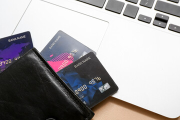 Poster - Laptop with leather wallet and credit cards on brown background