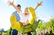 © Maria Sbytova - Happy little boy having fun in a wheelbarrow pushing by dad in domestic garden on warm sunny day. Active outdoors games for kids in summer.