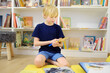 © Maria Sbytova - A preteen boy leafing through a book while sitting at the bookshelves in a school library or bookstore. Smart kid reading adventure book