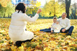 © ribalka yuli - A happy family of four spend time in the autumn park. Mother takes a picture of her family on a mobile phone