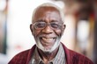 © Leon Waltz - Medium shot portrait photography of a happy Nigerian man in his 80s wearing a chic cardigan against an abstract background