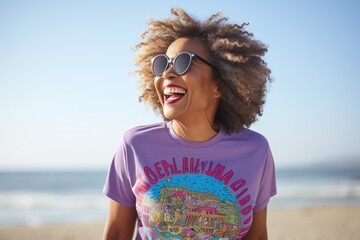 Lifestyle portrait photography of a pleased Nigerian woman in her 50s wearing a fun graphic tee against a beach background 